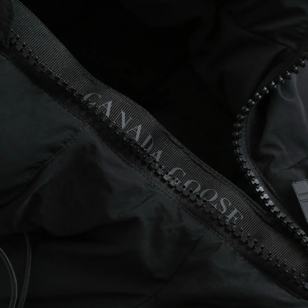 P1010 [Exclusive supply] Canada Goose Black Label Badge Hooded Down Jacket (Black) The high-quality filling is made of 90 national standard high-quality white duck down, selected high-loft velvet, weighing 240g, light and warm, with excellent temperature locking performance and good resilience. The fabric is woven with 400T high-count yarn. After special water-repellent treatment, the surface forms a lotus leaf effect - raindrops will slide down like beads, and snow particles will fall off when touched. The tear resistance reaches 200N (approximately 20kg load-bearing), the light gray matte texture breaks the stereotype of "outdoor clothing = hardcore", and the soft luster presents a high-end matte effect under urban neon lights, seamlessly switching scenes from ski resorts to CBD office buildings. The ribbon is woven with polyester as the base, and the brand letters are decorated on the ribbon through high-precision computer embroidery. The edges of the pattern are clear, the stitches are fine and even, and multiple layers of embroidery thread are stacked to enhance the three-dimensional effect. Precision thread reinforcement prevents linting and ensures the fluffy and resilient elasticity lasts as new. The embedded cuffs are three-dimensionally woven to form a "wavy" elastic structure, which forms natural folds when fitting the wrist, increasing the contact area with the skin, thus improving the windproof effect. At the same time, micro-velvet treatment is added to the inside of the cuffs, which feels like a second layer of skin and avoids friction on the skin from metal zippers or hard fabrics. Size:S-M-L-XL